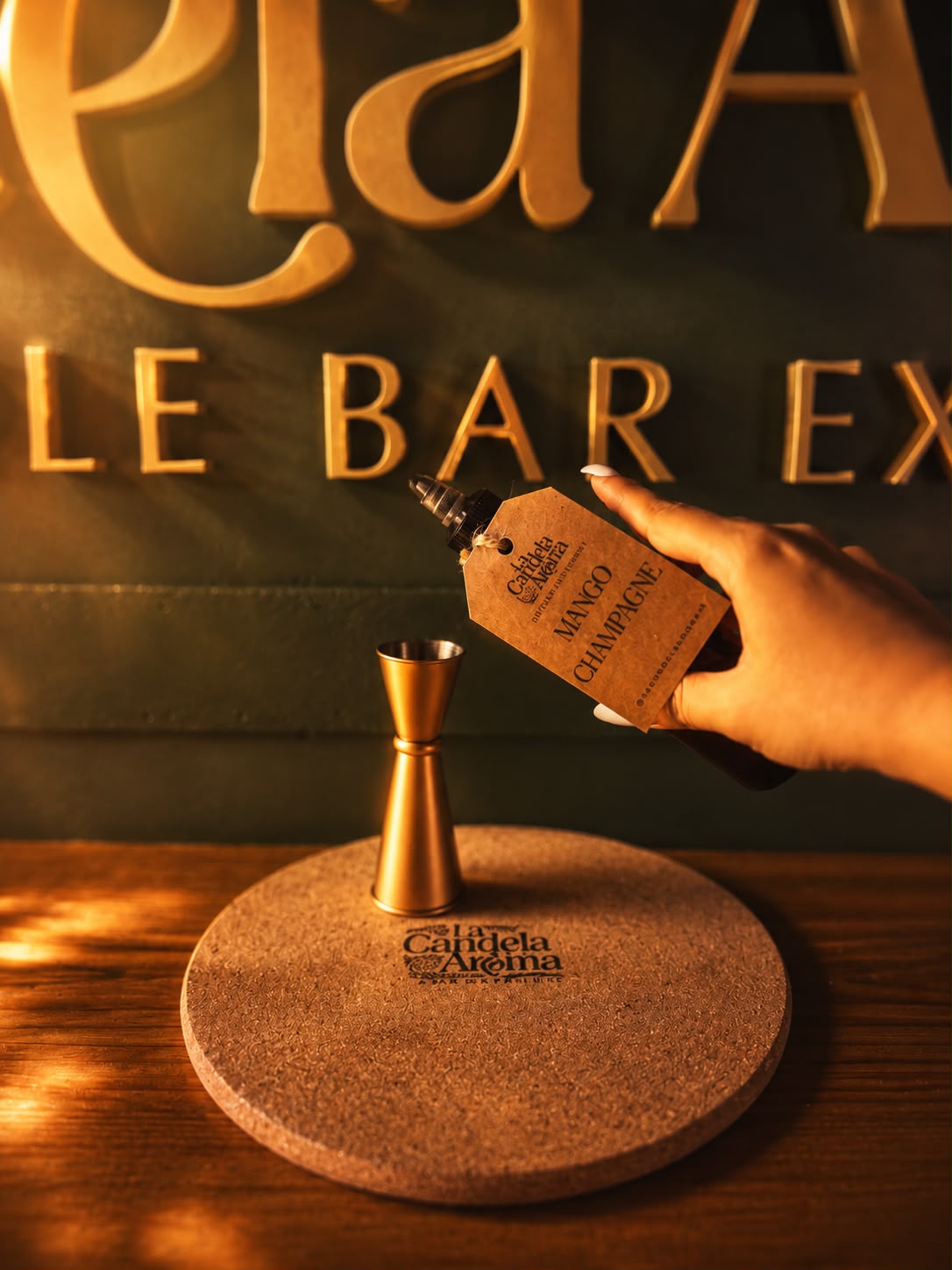 Mano sosteniendo un frasco de aroma Mango Champagne en el Candle Bar de La Candela Aroma PR